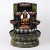 A resin table-top fountain featuring a statue of Lord Buddha, with water flowing around or from the statue.