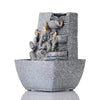 A small, tabletop fountain featuring a statue of Lord Ganesha, the Hindu god of wisdom and remover of obstacles. Water flows around or from the statue, creating a serene and calming atmosphere. The fountain may be made of stone, marble, or other materials and may have additional decorative elements, such as plants or lights