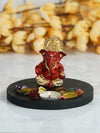 Handmade Ganesha idol in red and gold polyresin with a lotus-shaped tealight holder, showcasing intricate details. Ideal for altars and home decor."