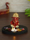 Handmade Ganesha idol in red and gold polyresin with a lotus-shaped tealight holder, showcasing intricate details. Ideal for altars and home decor."